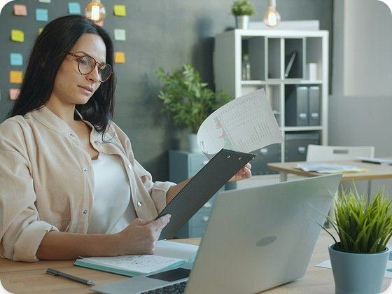 A buyer checking a printed report against her laptop